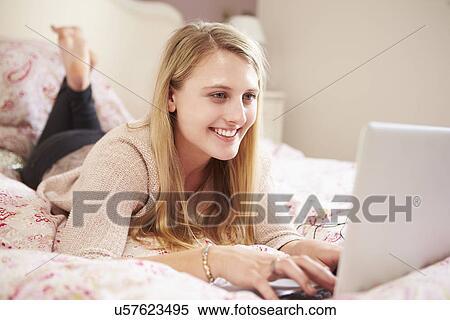 Stock Photography - Teenage Girl Lying On Bed Using Laptop. Fotosearch