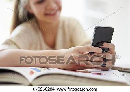 Teenage Girl Sending Text Message Whilst Studying On Laptop View Large Photo Image Picture - Teenage Girl Sending Text Message Whilst Studying On Laptop. Fotosearch