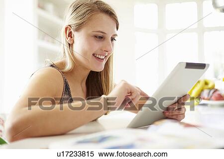 Stock Photography - Teenage Girl Studying Using Digital Tablet At Home. Fotosearch