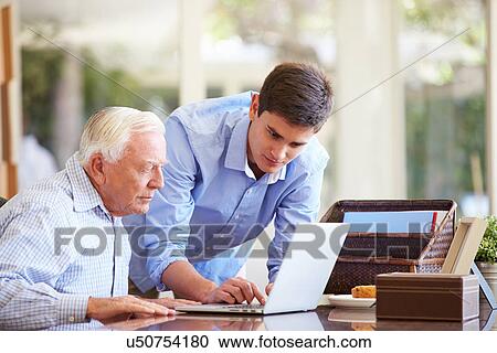 Stock Image - Teenage Grandson Helping Grandfather With Laptop. Fotosearch