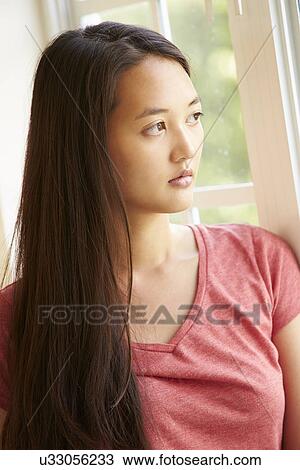 Stock Image - Thoughtful Asian Woman Looking Out Of Window. Fotosearch