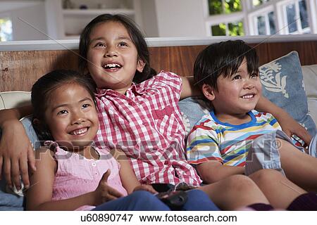 Three Asian Children Sitting On Sofa Watching TV Together View Large Photo Image Stock Photo - Three Asian Children Sitting On Sofa Watching TV Together. Fotosearch
