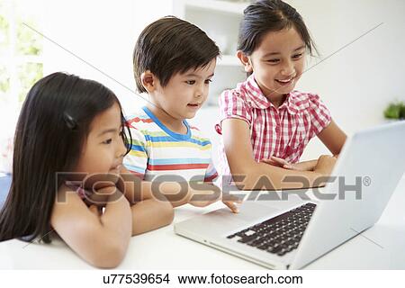 Picture - Three Asian Children Using Laptop At Home. Fotosearch