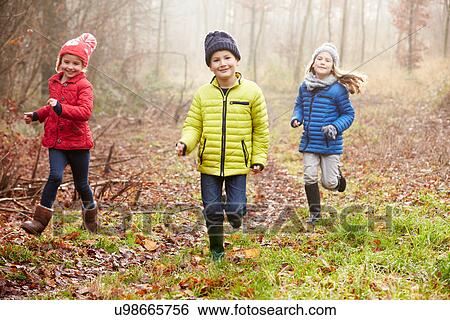 Stock Photograph - Three Children Running Through Winter Woodland. Fotosearch