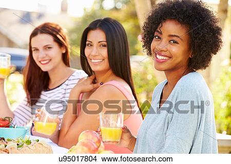 Picture - Three Female Friends Enjoying Meal At Outdoor Party. Fotosearch