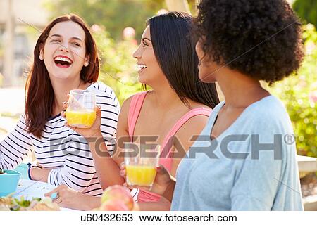 Stock Image - Three Female Friends Enjoying Meal At Outdoor Party. Fotosearch