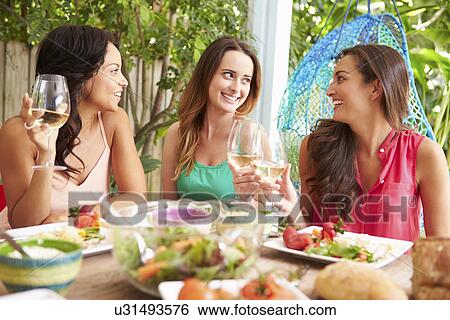 Stock Photograph - Three Female Friends Enjoying Meal Outdoors At Home. Fotosearch