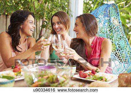 Stock Photograph - Three Female Friends Enjoying Meal Outdoors At Home. Fotosearch