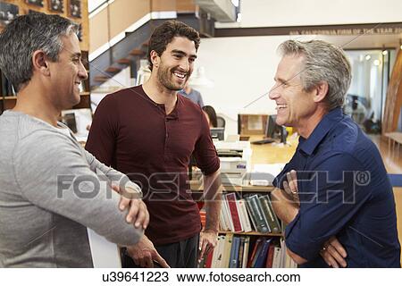 Stock Image - Three Male Architects Chatting In Modern Office Together. Fotosearch
