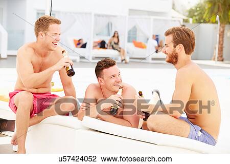 Stock Image - Three Young Male Friends On Holiday By Pool Together. Fotosearch