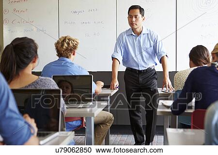 Stock Image - Tutor With High School Students In Class Using Laptops. Fotosearch