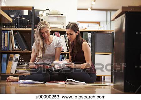 Stock Image - Two Businesswomen Sit On Office Floor With Digital Tablet. Fotosearch