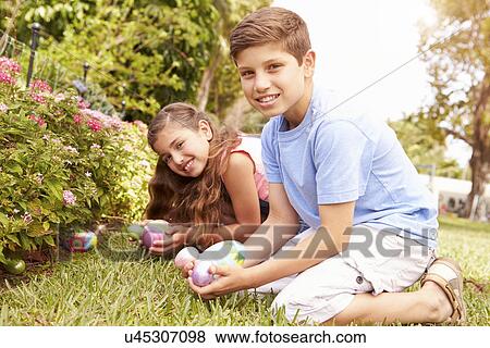Two Children Having Easter Egg Hunt In Garden View Large Photo Image Stock Photo - Two Children Having Easter Egg Hunt In Garden. Fotosearch