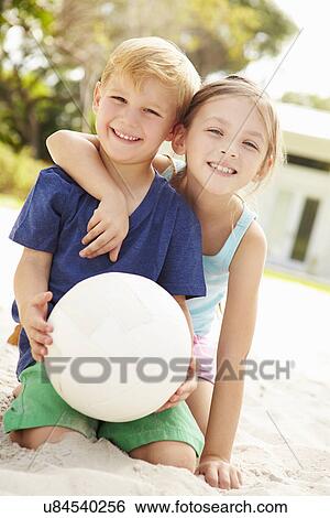 Stock Photograph - Two Children Playing Game Of Volleyball In Garden . Fotosearch