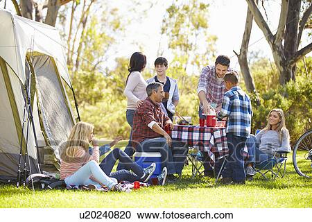 Stock Image - Two Families Enjoying Camping Holiday In Countryside. Fotosearch