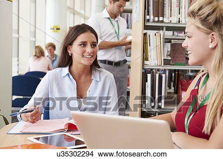 Picture - Two Female College Students Studying In Library Together. Fotosearch