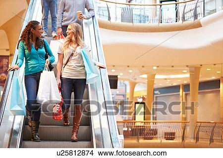 Picture - Two Female Friends On Escalator In Shopping Mall. Fotosearch