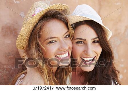 Stock Photo - Two Female Friends On Holiday Together Posing By Wall. Fotosearch