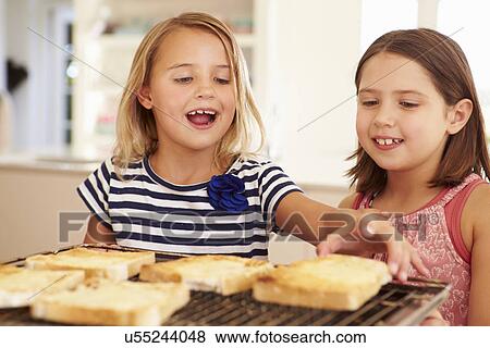Stock Photo - Two Girls Eating Cheese On Toast In Kitchen. Fotosearch