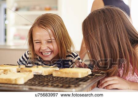 Two Girls Eating Cheese On Toast In Kitchen View Large Photo Image Stock Photo - Two Girls Eating Cheese On Toast In Kitchen. Fotosearch