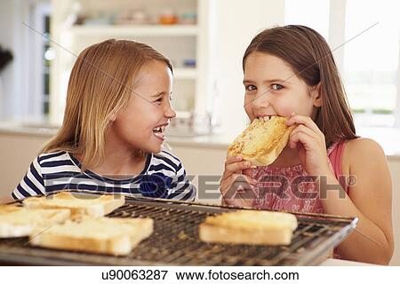 Two Girls Eating Cheese On Toast In Kitchen View Large Photo Image Stock Photo - Two Girls Eating Cheese On Toast In Kitchen. Fotosearch