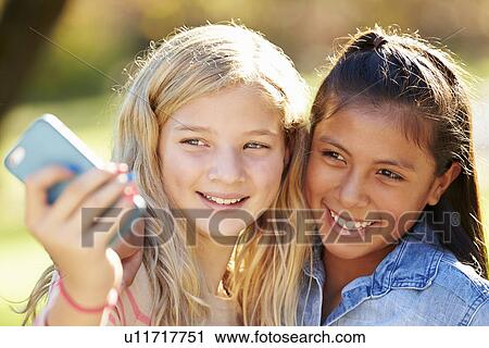 Stock Image - Two Girls Taking Selfie With Mobile Phone. Fotosearch