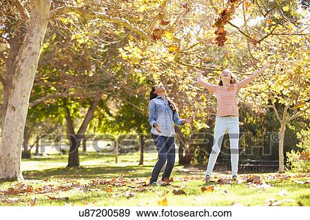 Two Girls Throwing Autumn Leaves In The Air View Large Photo Image Stock Photo - Two Girls Throwing Autumn Leaves In The Air. Fotosearch