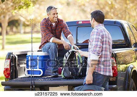 Stock Photography - Two Men Unpacking Pick Up Truck On Camping Holiday. Fotosearch