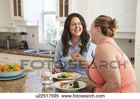 Stock Photography - Two Overweight Women On Diet Eating Healthy Meal In Kitchen. Fotosearch