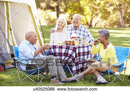 Stock Photo - Two Senior Couples Enjoying Camping Holiday In Countryside. Fotosearch