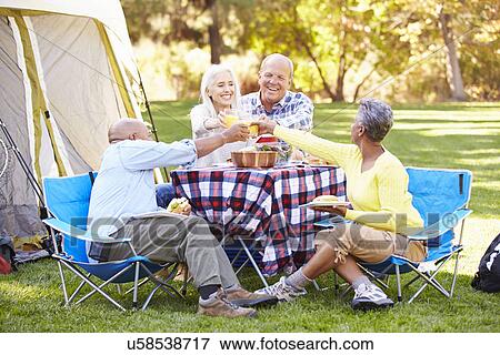Stock Photo - Two Senior Couples Enjoying Camping Holiday In Countryside. Fotosearch