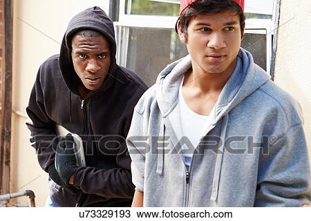Stock Image - Two Young Men Breaking Into House And Stealing Laptop. Fotosearch