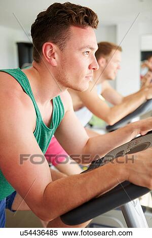 Stock Photography - Two Young Men Training In Gym On Cycling Machines Together. Fotosearch