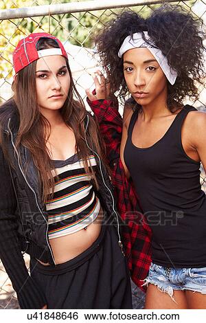 Two Young Women In Urban Setting Standing By Fence View Large Photo Image Stock Photograph - Two Young Women In Urban Setting Standing By Fence. Fotosearch