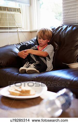Picture - Unhappy Boy Sitting On Sofa At Home. Fotosearch