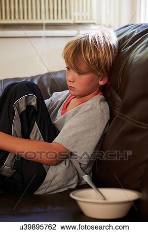 Stock Image - Unhappy Boy Sitting On Sofa At Home. Fotosearch