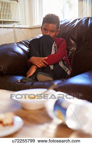 Stock Photo - Unhappy Boy Sitting On Sofa At Home. Fotosearch