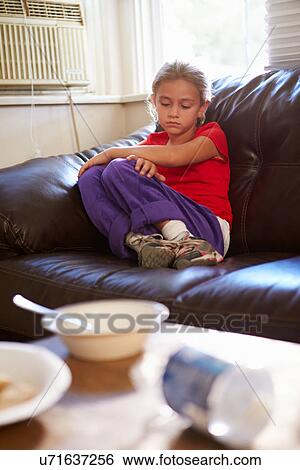 Stock Photograph - Unhappy Girl Sitting On Sofa At Home. Fotosearch