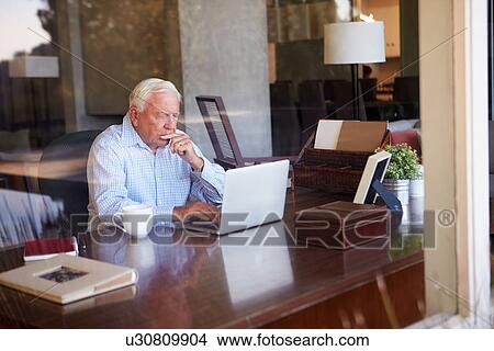 Picture - View Of Senior Man Using Laptop Through Window. Fotosearch