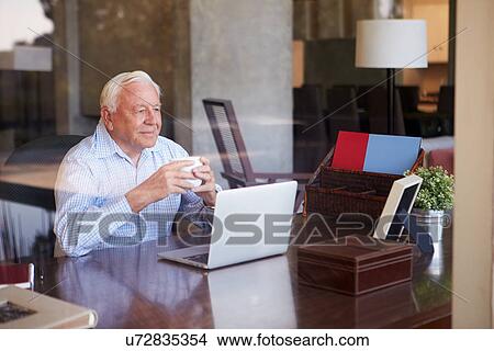 View Of Senior Man Using Laptop Through Window View Large Photo Image Picture - View Of Senior Man Using Laptop Through Window. Fotosearch