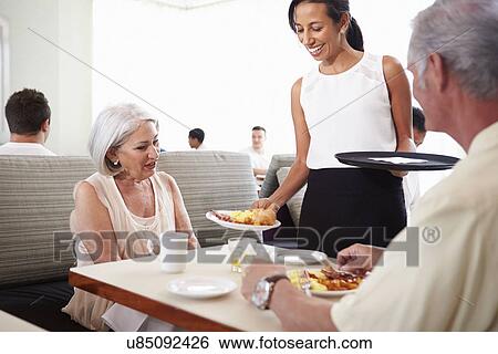 Stock Photograph - Waitress Serving Senior Couple Breakfast In Hotel Restaurant. Fotosearch