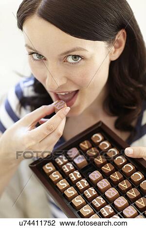 Stock Image - Woman eating chocolates. Fotosearch