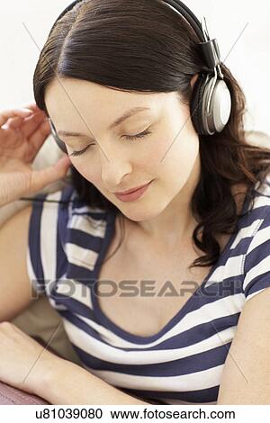 Woman listening to music through headphones View Large Photo Image Stock Image - Woman listening to music through headphones. Fotosearch