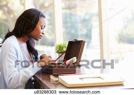 Stock Image - Woman Looking At Document In Keepsake Box On Desk. Fotosearch