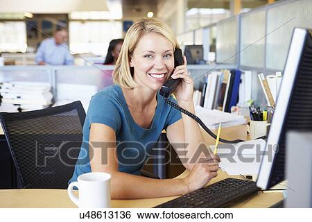 Stock Photograph - Woman On Phone In Busy Modern Office. Fotosearch