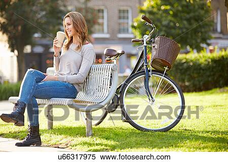 Stock Photography - Woman Relaxing On Park Bench With Takeaway Coffee. Fotosearch