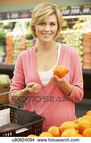 Picture - Woman shopping in supermarket. Fotosearch