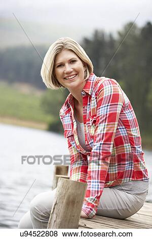 Woman sitting on a jetty View Large Photo Image Stock Photo - Woman sitting on a jetty. Fotosearch