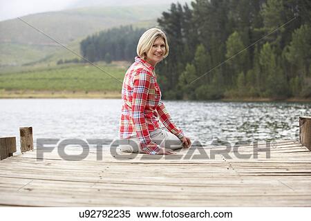 Woman sitting on a jetty View Large Photo Image Stock Photography - Woman sitting on a jetty. Fotosearch
