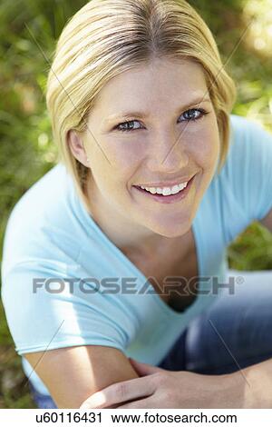 Woman sitting on grass View Large Photo Image Stock Image - Woman sitting on grass. Fotosearch